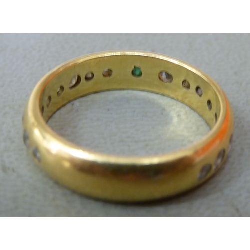 88 - An 18ct gold ring, set with an emerald and eighteen diamonds