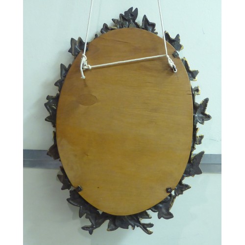 106 - A late 19thC mirror, in a cast iron gilt painted foliate design frame  19