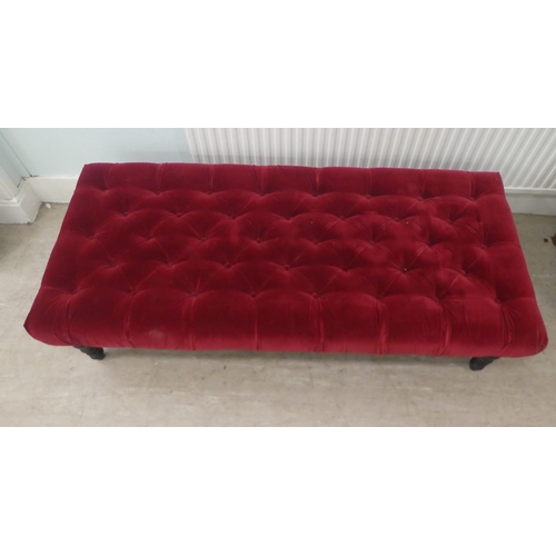 12 - A modern footstool, part button upholstered in red fabric, over a stained wooden frame