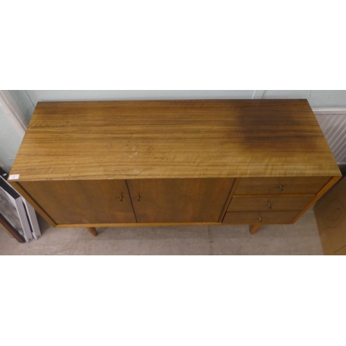 3 - A Vanson teak sideboard with a pair of cupboard doors, adjacent to three drawers, raised on turned l... 