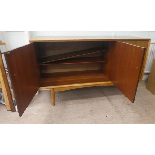 3 - A Vanson teak sideboard with a pair of cupboard doors, adjacent to three drawers, raised on turned l... 