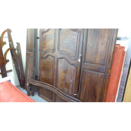 335 - An early 20thC panelled walnut armoire, enclosed by a pair of full height doors, raised on short cab... 