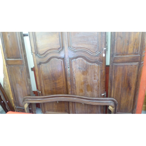 335 - An early 20thC panelled walnut armoire, enclosed by a pair of full height doors, raised on short cab... 