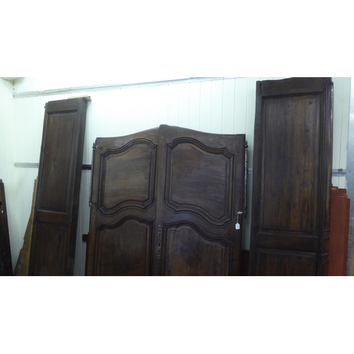 335 - An early 20thC panelled walnut armoire, enclosed by a pair of full height doors, raised on short cab... 