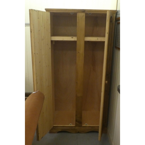 43 - A modern pine effect two door wardrobe, on a bracket plinth  42