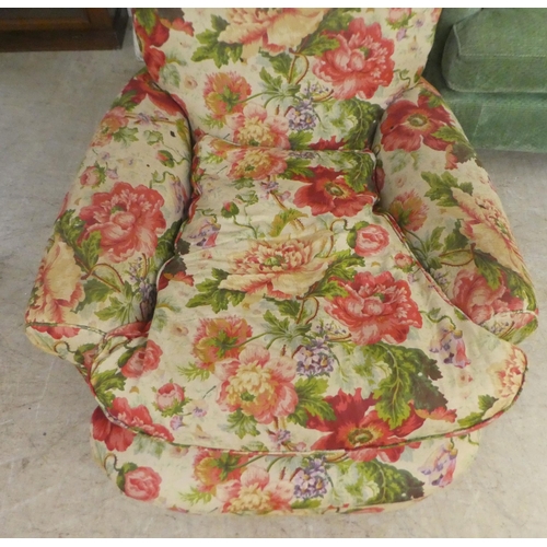 47 - An early 20thC floral patterned fabric upholstered, low, enclosed armchair, raised on block feet&nbs... 