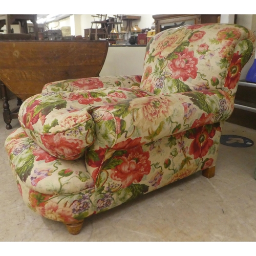 47 - An early 20thC floral patterned fabric upholstered, low, enclosed armchair, raised on block feet&nbs... 