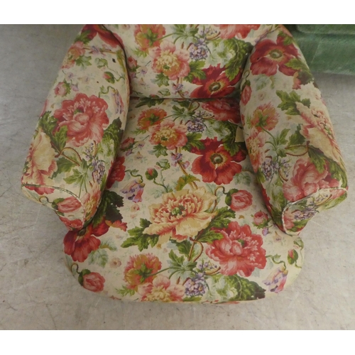 47 - An early 20thC floral patterned fabric upholstered, low, enclosed armchair, raised on block feet&nbs... 