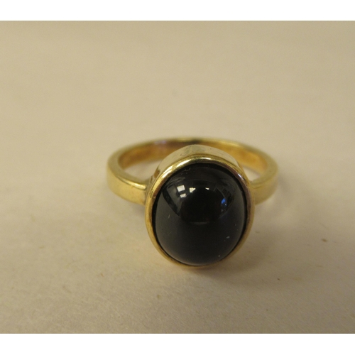 64 - A gold coloured metal ring, set with a star sapphire  