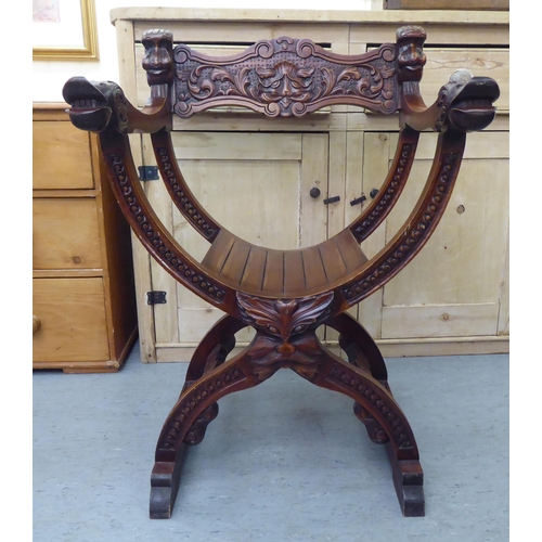 68 - A 20thC Savonarola design lacquered mahogany framed chair with C-scrolled, foliate and mask carved o... 