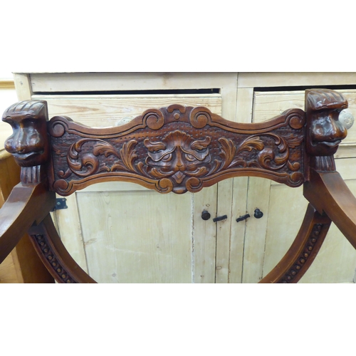 68 - A 20thC Savonarola design lacquered mahogany framed chair with C-scrolled, foliate and mask carved o... 