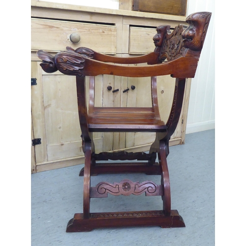 68 - A 20thC Savonarola design lacquered mahogany framed chair with C-scrolled, foliate and mask carved o... 