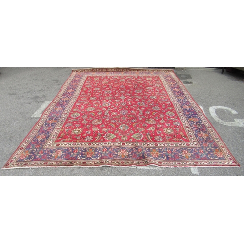 69 - A Persian carpet, decorated with flora and foliate designs, on a mainly red ground with a dark blue ... 