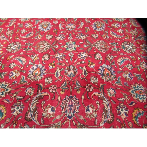 69 - A Persian carpet, decorated with flora and foliate designs, on a mainly red ground with a dark blue ... 