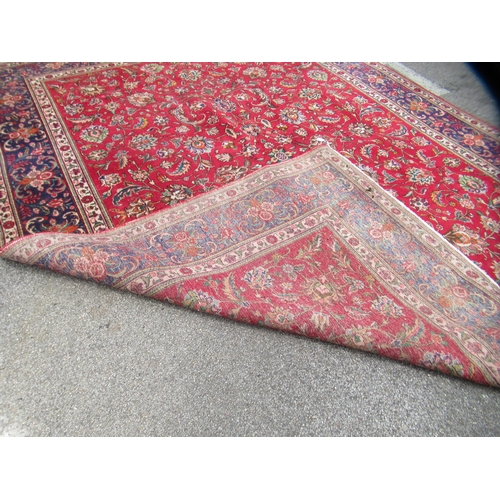 69 - A Persian carpet, decorated with flora and foliate designs, on a mainly red ground with a dark blue ... 