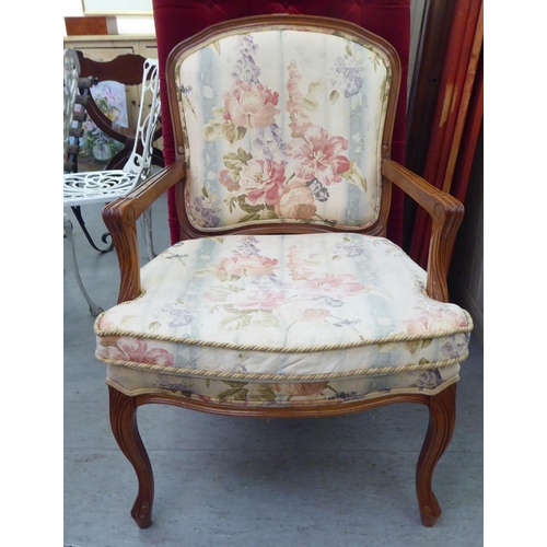 73 - A modern French design carved beech framed open armchair with floral fabric upholstery and a cushion... 