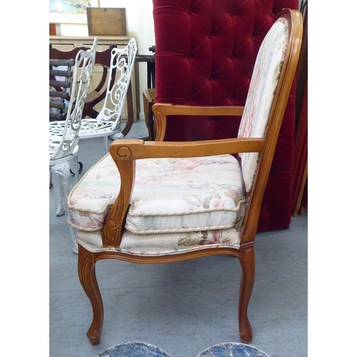 73 - A modern French design carved beech framed open armchair with floral fabric upholstery and a cushion... 