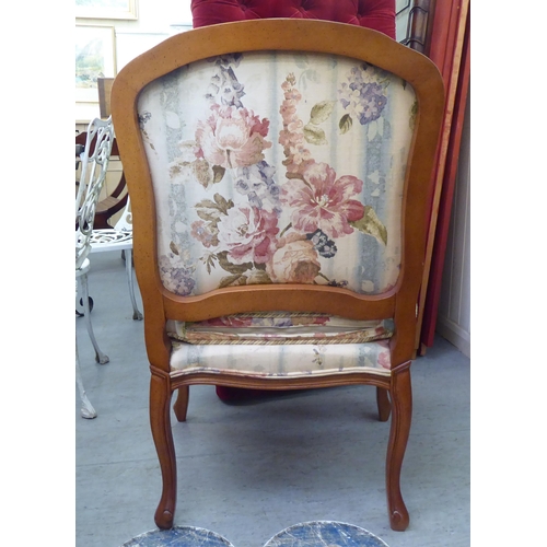 73 - A modern French design carved beech framed open armchair with floral fabric upholstery and a cushion... 