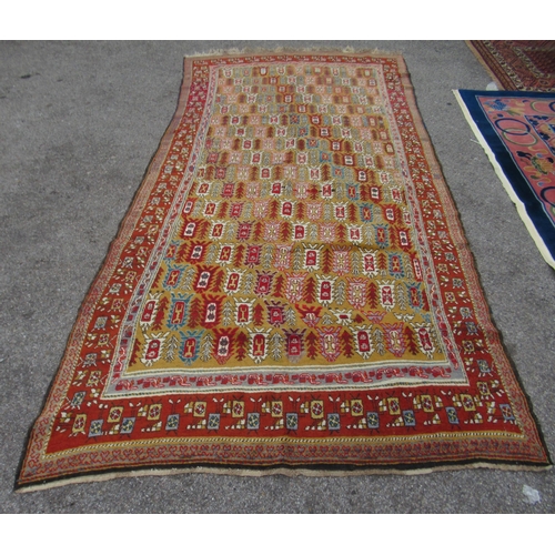 80 - A Persian rug, decorated with small tree inspired designs within a red border, on a multi-coloured g... 
