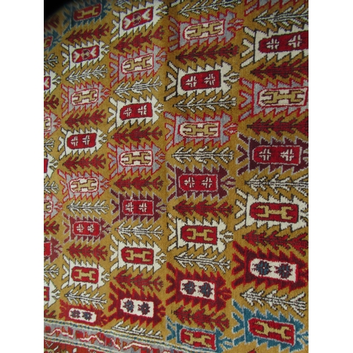 80 - A Persian rug, decorated with small tree inspired designs within a red border, on a multi-coloured g... 