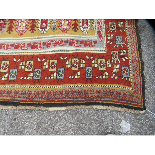 80 - A Persian rug, decorated with small tree inspired designs within a red border, on a multi-coloured g... 