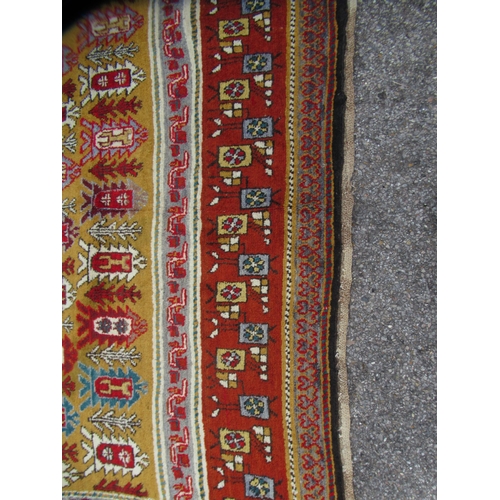 80 - A Persian rug, decorated with small tree inspired designs within a red border, on a multi-coloured g... 