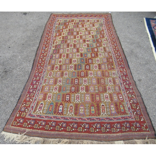 80 - A Persian rug, decorated with small tree inspired designs within a red border, on a multi-coloured g... 