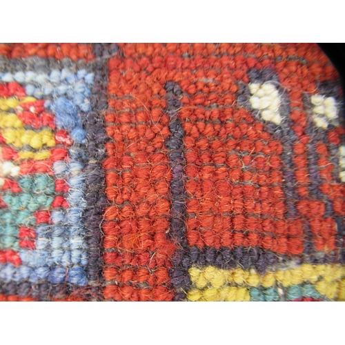 80 - A Persian rug, decorated with small tree inspired designs within a red border, on a multi-coloured g... 