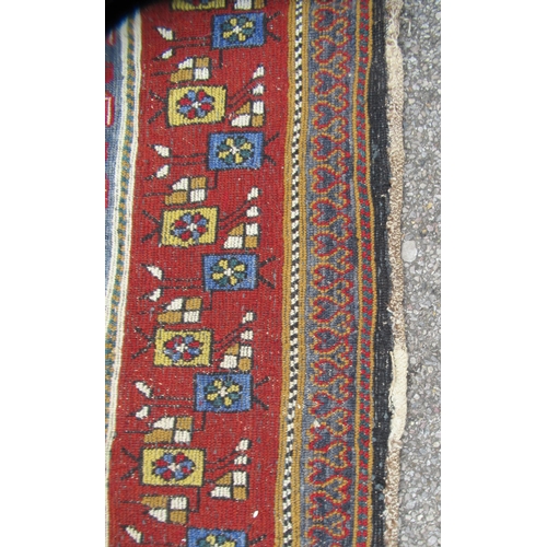 80 - A Persian rug, decorated with small tree inspired designs within a red border, on a multi-coloured g... 