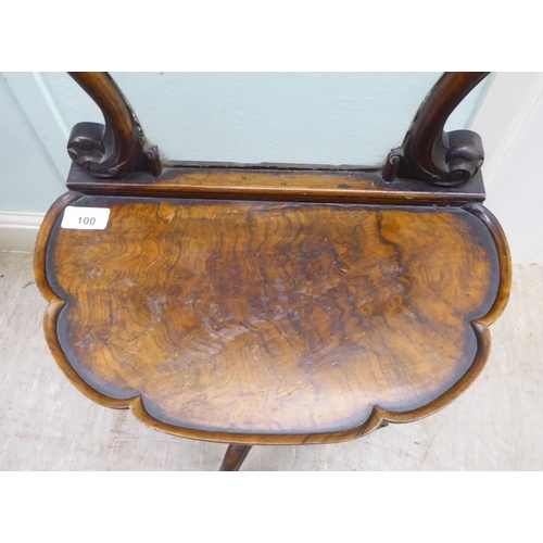 100 - A Victorian walnut dressing room pedestal table with a carved upstand glazed frame, on a scalloped e... 