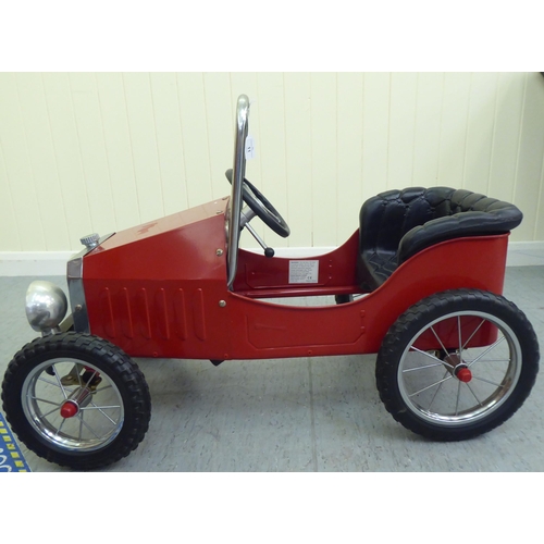 11 - A painted model pedal car, in the manner of a veteran vehicle with red livery and spoked rubber whee... 