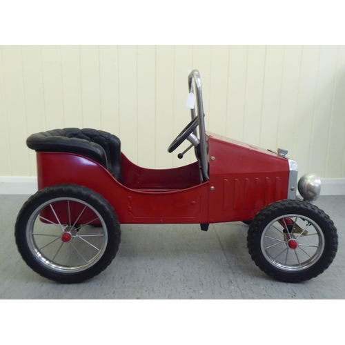 11 - A painted model pedal car, in the manner of a veteran vehicle with red livery and spoked rubber whee... 