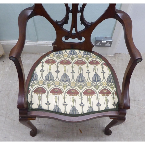 133 - An Art Nouveau style Jones & Higgins mahogany framed chair with an open foliate scroll carved an... 