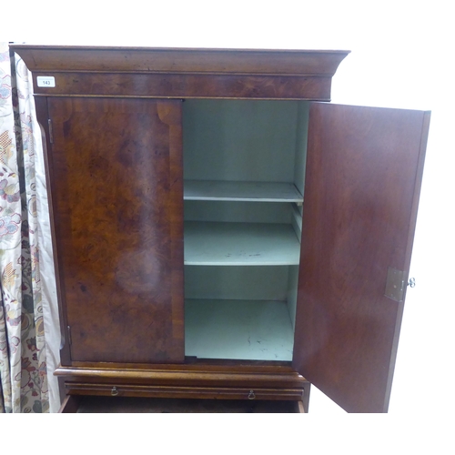 143 - A 1930s design walnut finished cocktail cabinet, the upper part enclosed by a pair of doors, over a ... 