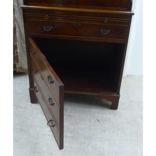 143 - A 1930s design walnut finished cocktail cabinet, the upper part enclosed by a pair of doors, over a ... 