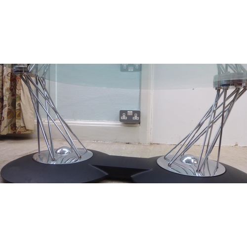 152 - A modern chromium plated steel wire framed eclipse type table, comprising two plate glass tops, rota... 