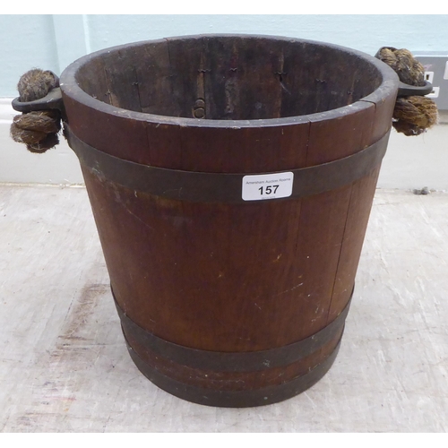 157 - An early 20thC rustically constructed coopered oak bucket with brass bands and a stitched hide sleev... 