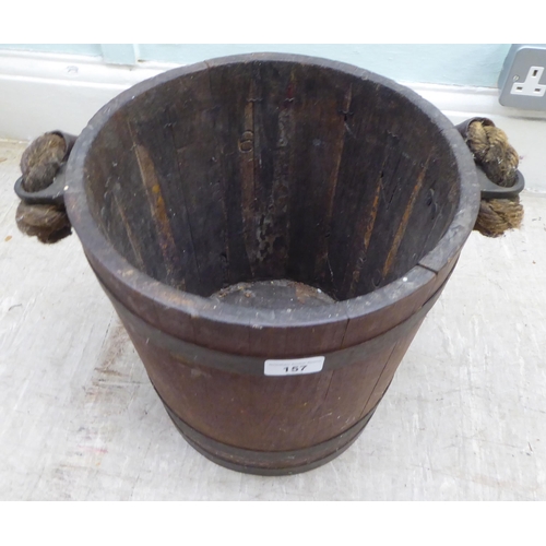 157 - An early 20thC rustically constructed coopered oak bucket with brass bands and a stitched hide sleev... 