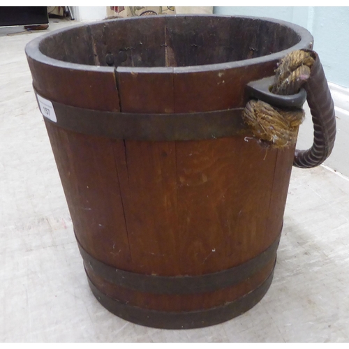 157 - An early 20thC rustically constructed coopered oak bucket with brass bands and a stitched hide sleev... 