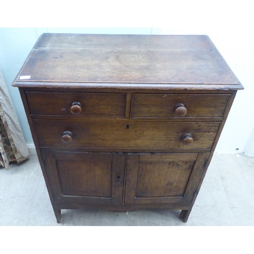 158 - An early 20thC oak cupboard, comprising two short/one long drawers, over a pair of panelled doors, r... 