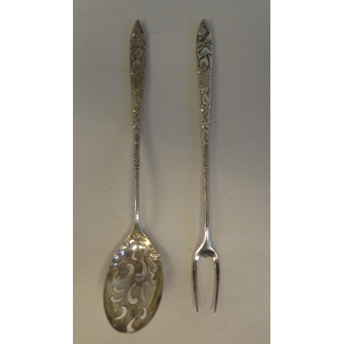 160 - A Liberty & Co silver coloured metal olive spoon and fork, on decoratively cast handles 