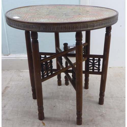 162 - An early 20thC North African coloured stained brass topped tray table, set on a folding beech stand&... 