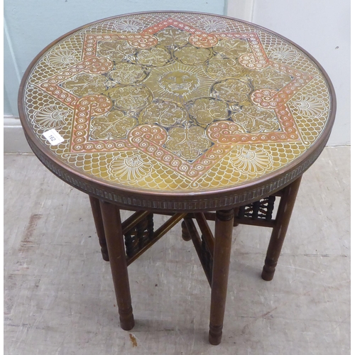 162 - An early 20thC North African coloured stained brass topped tray table, set on a folding beech stand&... 