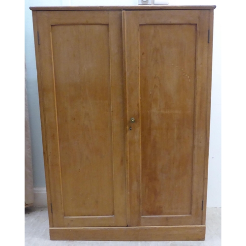 166 - An early 20thC waxed pine cupboard, enclosed by a pair of full height doors  53