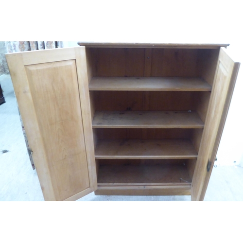 166 - An early 20thC waxed pine cupboard, enclosed by a pair of full height doors  53