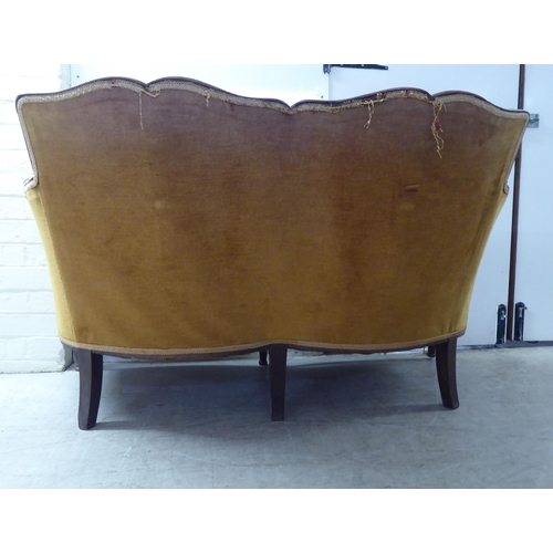 216 - An early 20thC stained beech showwood framed two person settee, upholstered in old gold/orange colou... 