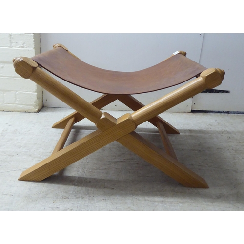 221 - A modern light oak framed and hide panelled stool 