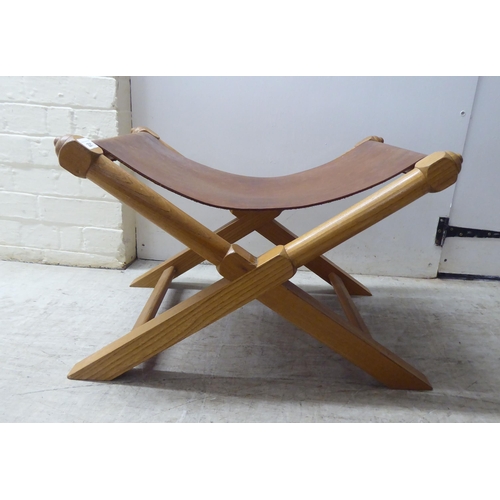 221 - A modern light oak framed and hide panelled stool 