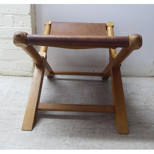 221 - A modern light oak framed and hide panelled stool 