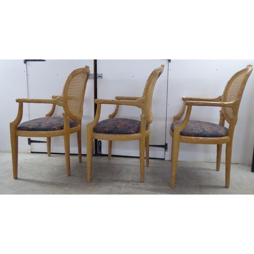 246 - A set of six modern natural oak effect framed dining chairs with a caned panel back, over a fabric c... 